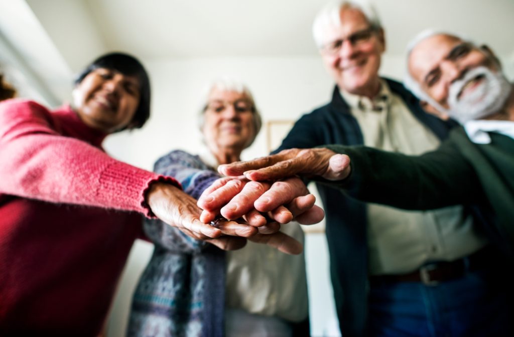 A group of seniors with their hands in the middle symbolizing teamwork and friendship