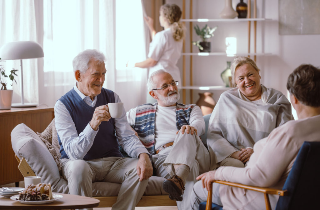 A group of seniors who are living in a senior living community happily conversing with each other.