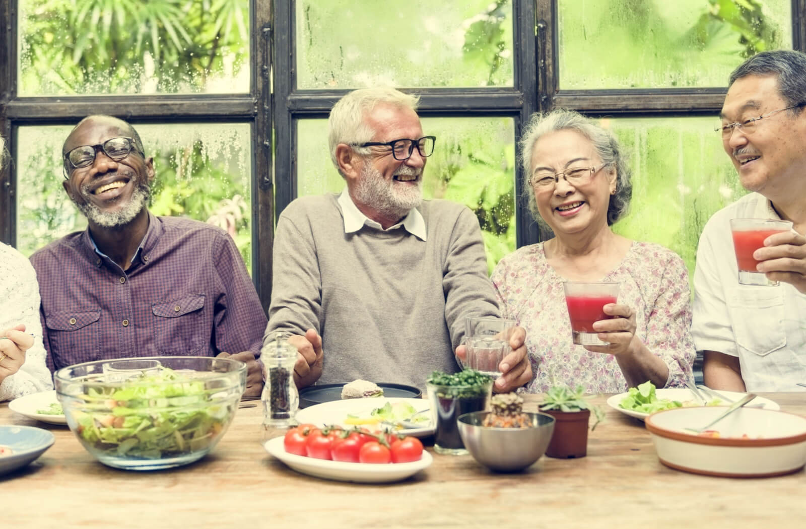 A group of seniors joyfully sharing laughter and relishing their meal during dinner at a senior living community.