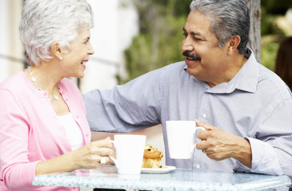 Elderly couple chatting casually and delighting in snacks outdoors.