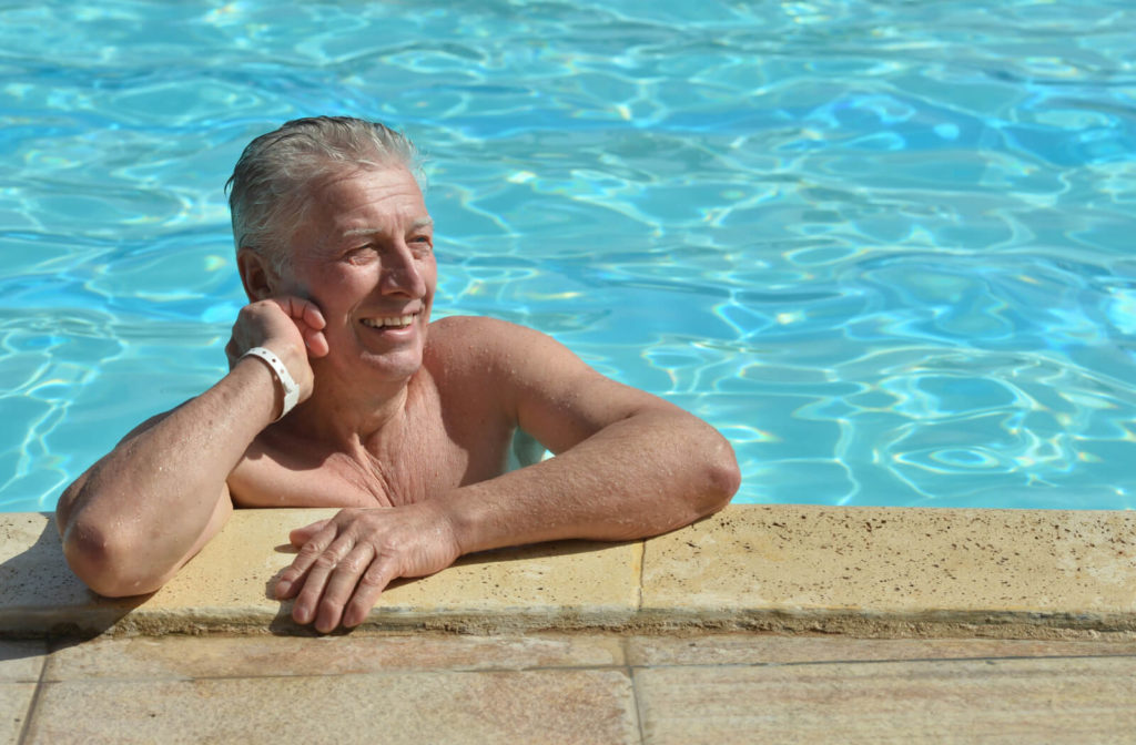 a senior man lounges in a pool in assisted living in florida
