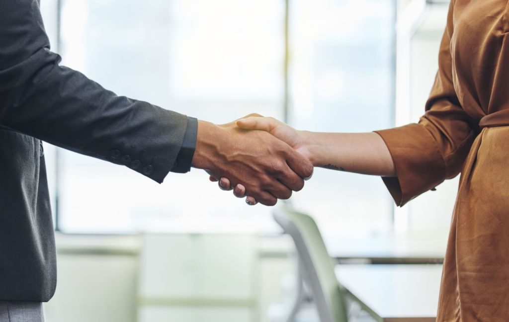 Two people are shaking hands after reaching an management partnership for their senior living community.