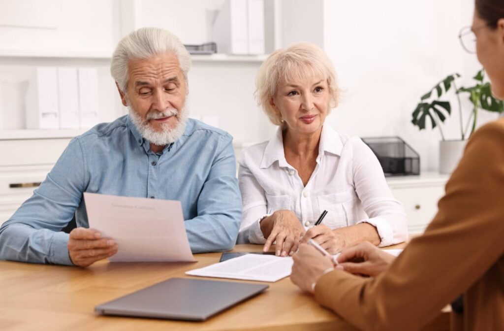 Two older adults examine paperwork while sitting in an office with an advisor