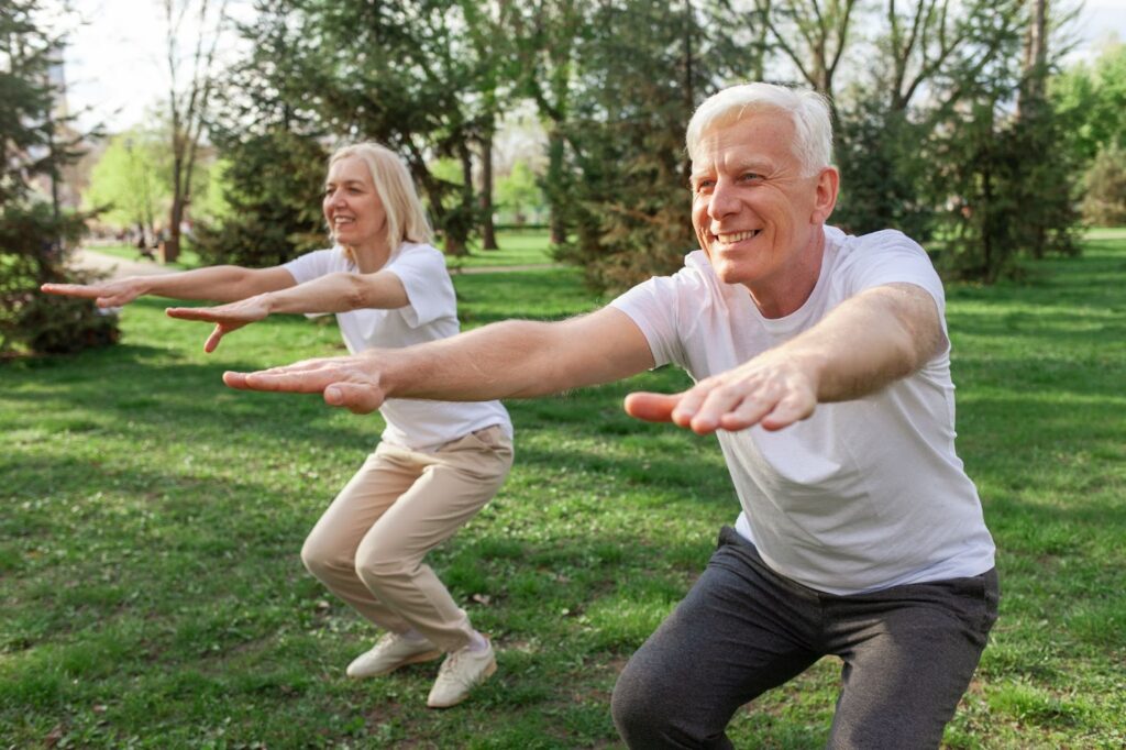 two seniors do yoga in a park