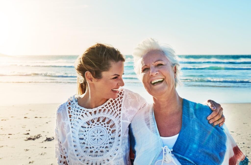 a young person and a senior laugh on a beach